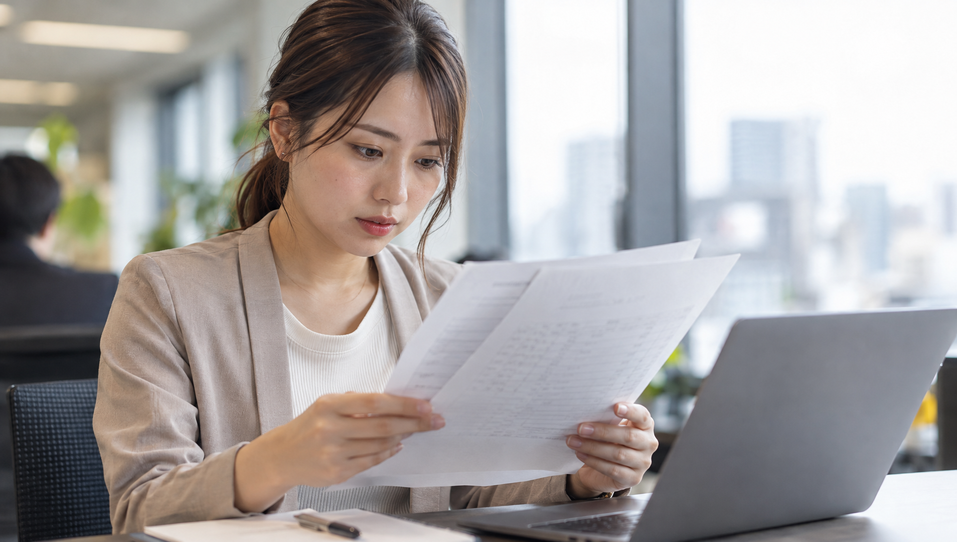 20代の女性がオフィスで見積書を確認している写真
